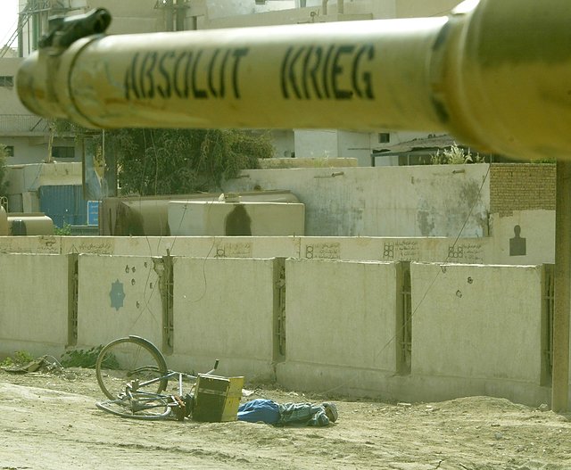 Chłopiec zastrzelony przez amerykańskiego żołnierza. Napis na lufie czołgu znaczy po niemiecku: bezwzględna wojna.