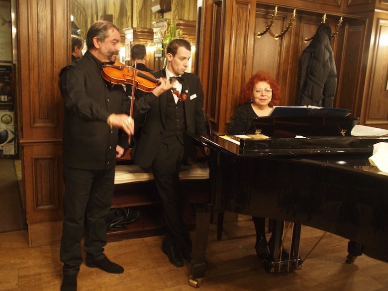 Muzycy i kelner koncertują w kawiarni Schwarzenberg.