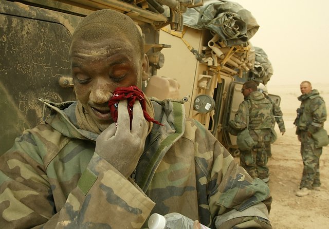 Żołnierz 70 pancernej wyciera twarz z kurzu na pustyni w Iraku.