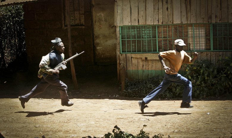 Kenijski policjant biegnie za demonstrantem w miejscowości Nderi.