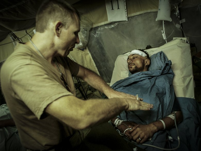 Amerykański lekarz bada więźnia rannego w moździerzowym ataku na wiezienie Abu Ghraib.