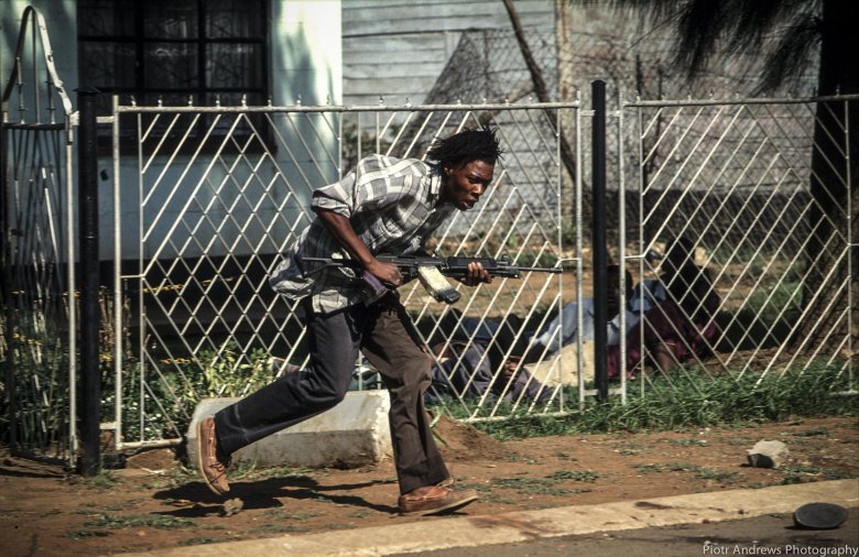 Bojownik ANC biegnie z kałasznikowem podczas walk z członkami IFP w Takozie.