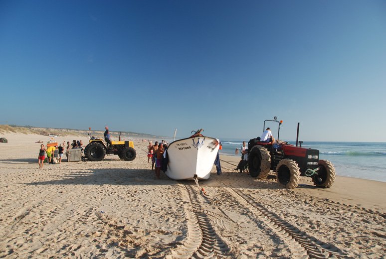 Łódź już po powrocie na ląd i traktory wyciągające sieć z wody.