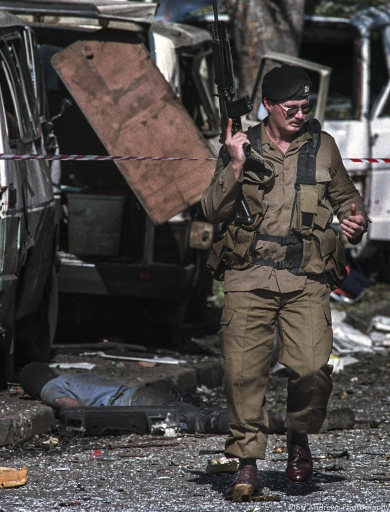 Policjant przechodzi kolo ciała jednej z ofiar eksplozji bomby. Zamach przeprowadzono koło głównej siedziby ANC w centrum Johannesburga .