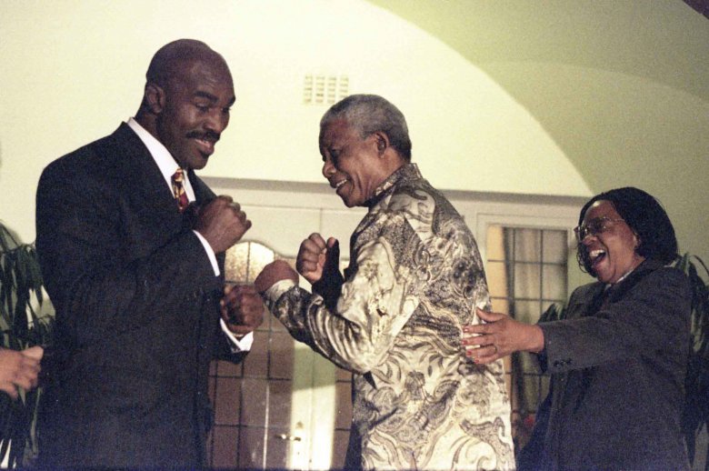 Prezydent Nelson Mandela przyjmuje pozycje walki z byłym mistrzem swiata Evenderem Holiefield  podczas gdy żona Mandeli, Graca Machel próbuje go odciągnąć.