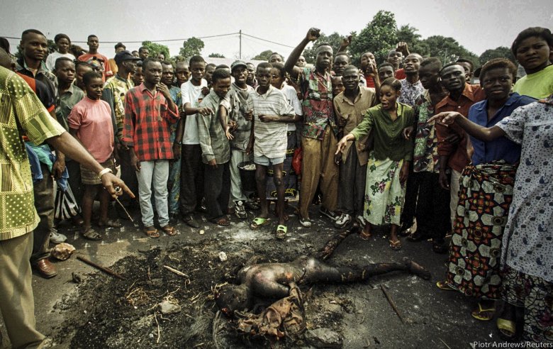 Tłum pokazuje spalone ciało mężczyzny z plemienia Tutsi