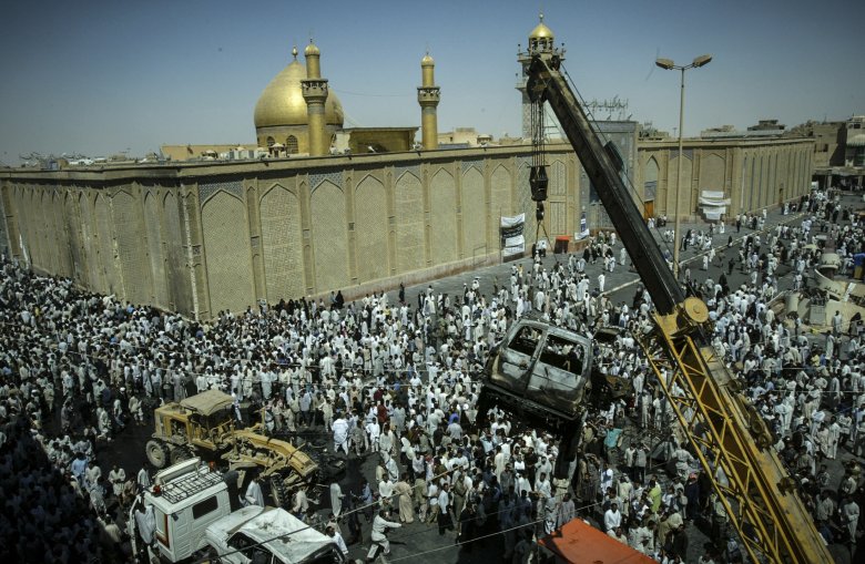 Dźwig podnosi  samochód, który spłonął po zamachu bombowym w mieście Nadżaf. W zamachu zginał jeden z głównych szyickich przywódców religijnych ajatollah Al. Hakim.