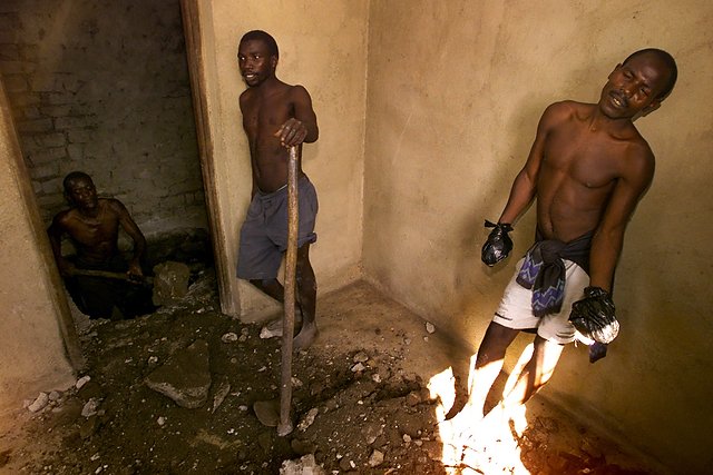 Wyczerpani więźniowie w chwili odpoczynku od pracy przy ekshumacji ciał ukrytych pod podłogą domu należącego do przywódcy sekty.